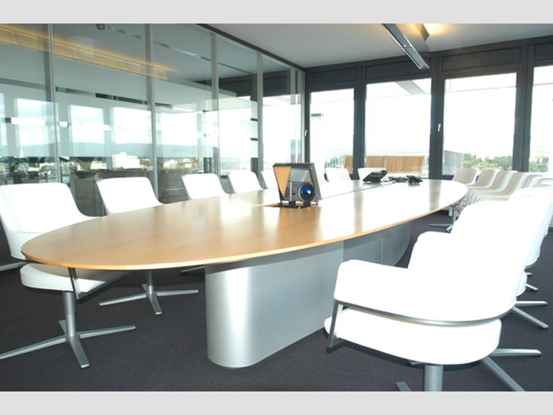 ovaler Konferenztisch mit weißen Stühlen und Beamer
